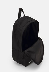 Sac à dos noir en tissu durable, doté d'une fermeture éclair et d'une poignée supérieure. L'intérieur est spacieux sans compartiments visibles.