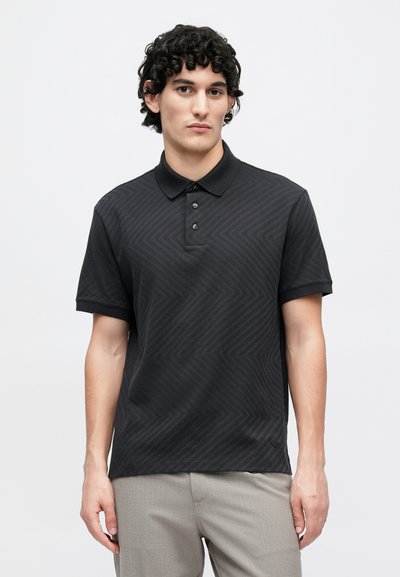 Melna polo krekls no teksturētas auduma ar smalku četrstūra rakstu, trīs pogu aizdare un īsām piedurknēm. Piestāvīga siluets.