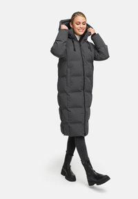 Long, gray, puffer coat with a hood, featuring a zip closure, side pockets, and a quilted pattern, paired with black jeans and boots.