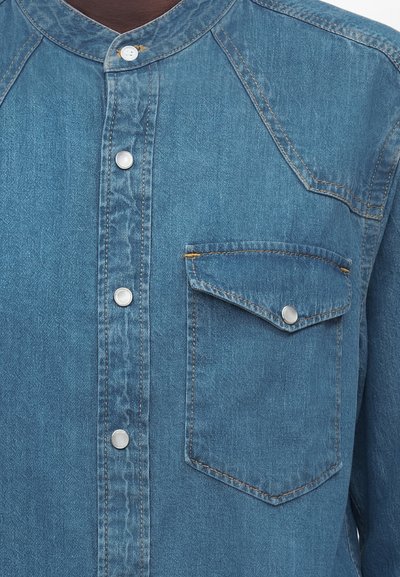 Τζιν πουκάμισο με γιακά μανταρίνι, κουμπώματα μπροστά με κλιπ και τσέπη στο στήθος με κουμπωτό καπάκι.