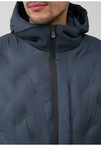 Granatowa kurtka puchowa z kapturem, posiadająca wysoki kołnierz, zapięcie na zamek błyskawiczny z przodu oraz teksturowaną górną część tkaniny, zaprojektowana z myślą o ciepłe i stylu.