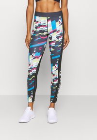 Svarta kompressionsleggings med ett digitalt mönster i blått, rosa och gult. Har ett brett midjeband och logotypdetalj på sidan.