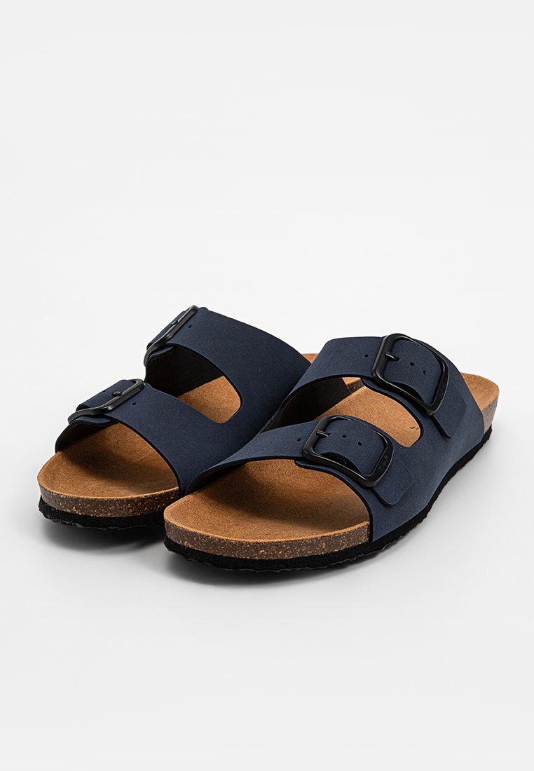 Sandales bleu marine avec deux brides ajustables, boucles noires, semelle en liège et semelle extérieure en caoutchouc texturé. Design simple et ouvert sur l'avant.
