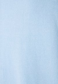 Ljust blått stickat tyg med en jämn, enhetlig textur som visar ett enhetligt mönster utan synliga sömmar eller anmärkningsvärda detaljer.