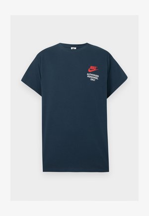 Tamno plavi pamučni majica s kratkim rukavima. Sadrži crveni Nike logo i bijeli natpis "SAMO OBLASTI OSOBLJE" na lijevom prsnom dijelu.