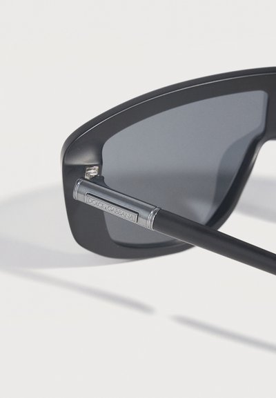 Μαύρα ορθογώνια γυαλιά ηλίου με σκούρους φακούς και ασημένια λεπτομέρεια στο σκελετό με χαραγμένο το λογότυπο «Dolce & Gabbana».