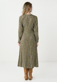 Robe longue à motifs dans des tons terreux avec un corsage ajusté et une jupe fluide. Dotée de manches longues et d'un col rond. Mise en valeur par un imprimé unique.