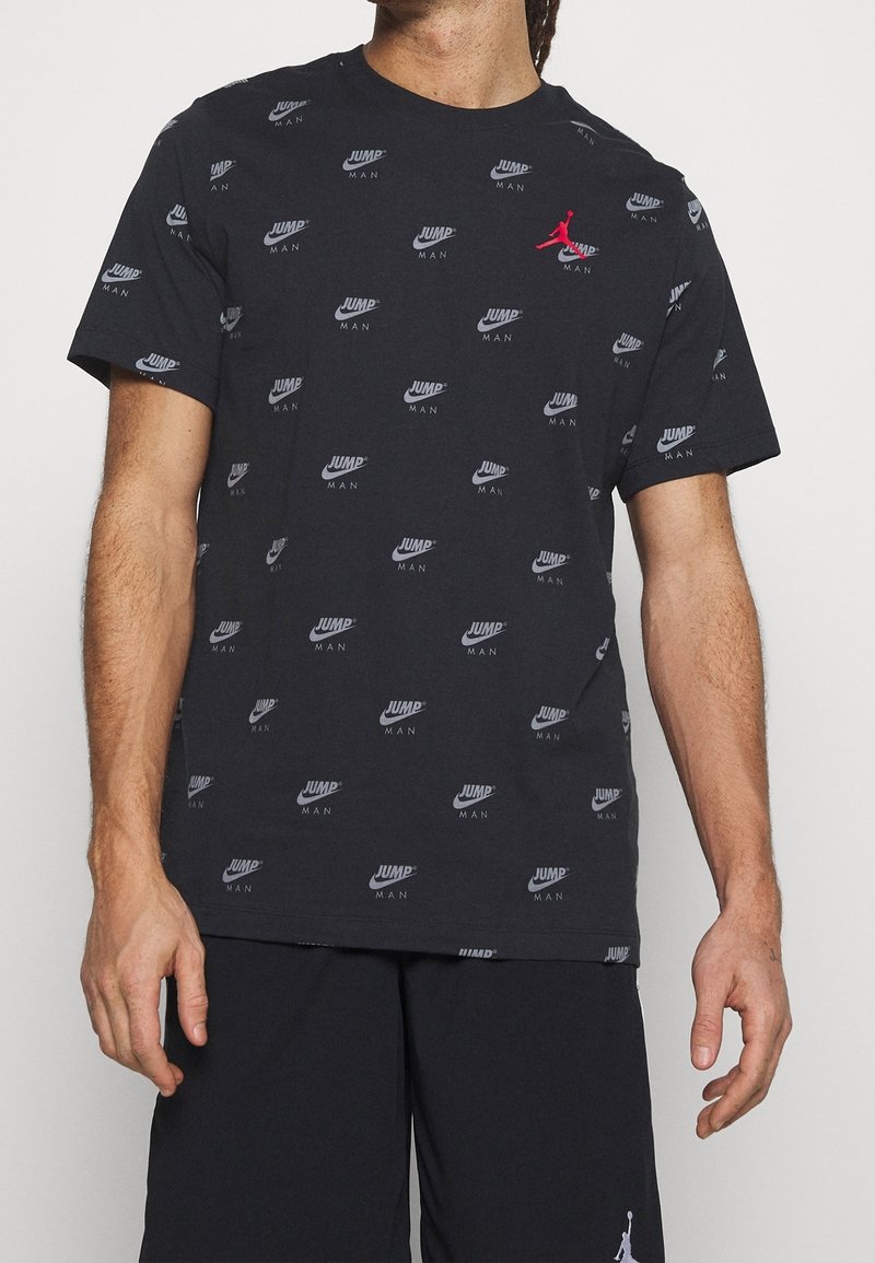 Camiseta negra con estampado de logotipos en toda la prenda, incluyendo "JUMP" y "MAN". Presenta mangas cortas, cuello redondo y material de algod�ón suave.