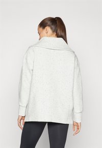 Ανοιχτό γκρι oversize μπουφάν με υφασμάτινο μοτίβο, φαρδύ γιακά και χαμηλούς ώμους; κατασκευασμένο από μαλακό ύφασμα με λεπτές βυθίσεις.