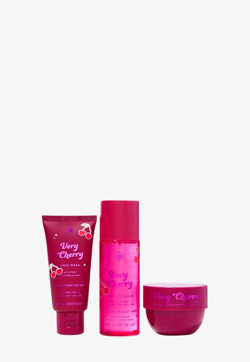 Tre prodotti per la cura della pelle rosa della linea "Very Cherry": un tubo, una bottiglia spray e un barattolo, tutti con grafiche e il logo a tema ciliegia.