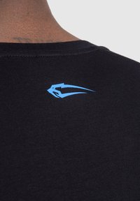 Camisa negra de manga corta con textura acanalada, que presenta un pequeño logo azul en la parte posterior cerca del escote.