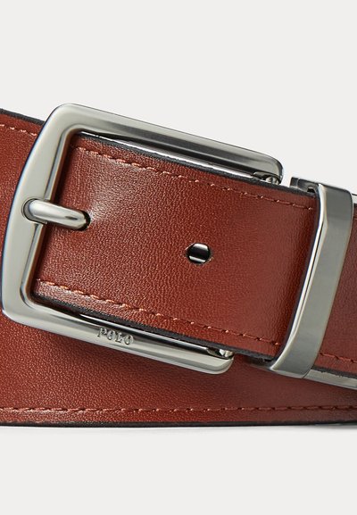 Cintura in pelle marrone con fibbia rettangolare d'argento incisa con la scritta "POLO", con la linguetta della fibbia inserita in un foro.