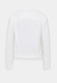 Biała teksturowana kurtka z długimi rękawami i postrzępionymi krawędziami przy dekolcie i dole. Posiada tkany wzór i luźny krój.