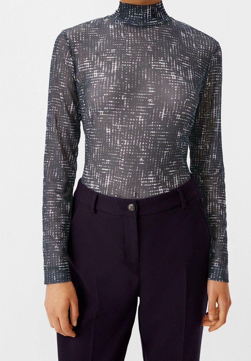 Lang mouwen bodysuit met hoge hals in doorzichtig grijs gaas met een wit abstract patroon, gecombineerd met donkerpaarseTailored broek met een knoopsluiting.
