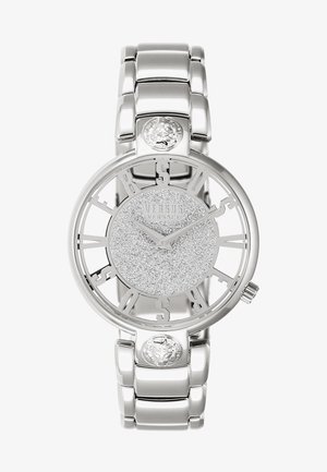 Montre-bracelet argentée Versus Versace avec cadran scintillant, chiffres ouverts formant le mot Versus, détails tête de lion sur le bracelet et bracelet métal relié.
