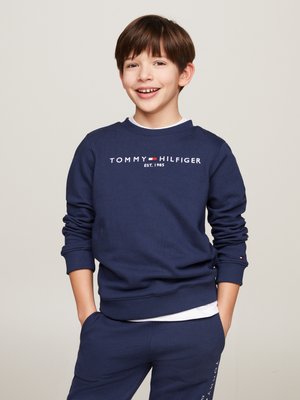 Mørkeblå hettegenser med ribbestrikkede mansjetter og nederkant, med hvit "TOMMY HILFIGER EST. 1985" logo over brystet. Myk bomullsmateriale.