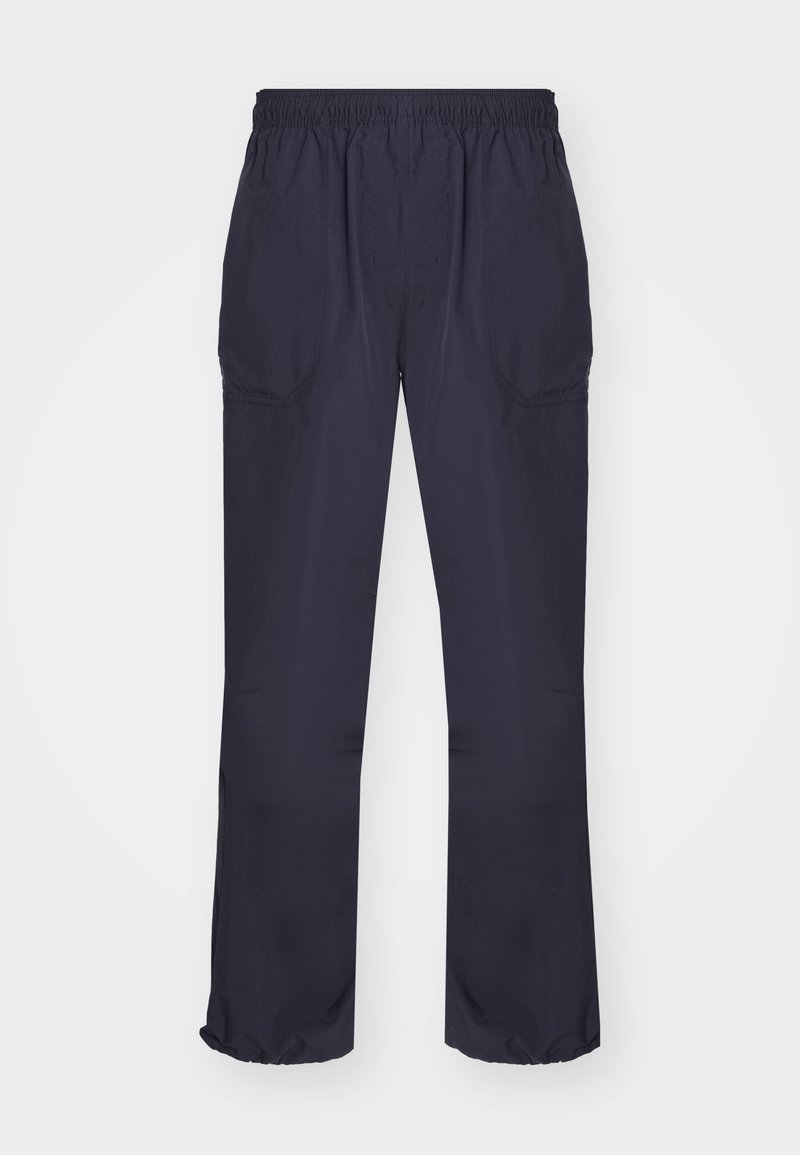 Pantalons de sport bleu marine avec une taille élastique, des poches latérales et des poignets élastiques aux chevilles, fabriqués en tissu léger.