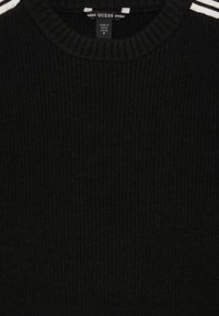 Maglione nero a coste con scollo rotondo e accenti a strisce bianche sulle spalle, realizzato in morbido tessuto a maglia. Taglia 8.