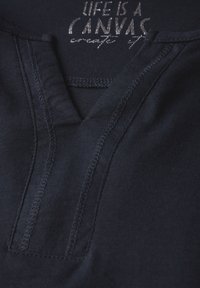 Navyblaue Baumwoll-T-Shirt mit V-Ausschnitt, ausgestattet mit einem strukturierten Stoff und silberfarbener Druckschrift mit dem Text "DAS LEBEN IST EIN LEINWAND." Sichtbare Nähdetails.