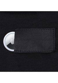 Dispositivo di tracciamento circolare bianco parzialmente infilato in un cinturino in pelle nera su uno sfondo in tessuto nero.