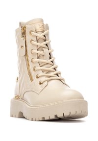 Bottine en toile beige à lacets avec une fermeture éclair sur le côté, motif matelassé, semelle épaisse et accents en metal doré. Matériau synthétique lisse.