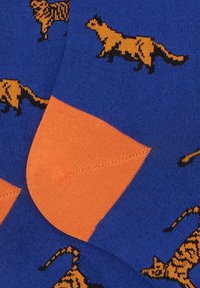 Calzini blu con accenti arancioni, caratterizzati da un motivo di tigri nere e arancioni. Realizzati in morbido materiale a maglia, mostrati alla caviglia.