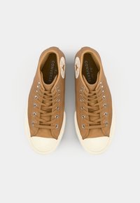 Brune kanvas høye sneakers med rund tå, hvit gummisåle, metallhull og stjernelogo-patch på yttersiden.