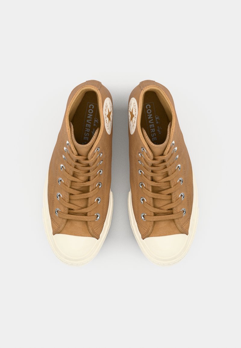 Sneakers alte in tela marrone con punta rotonda, suola in gomma bianca, occhielli in metallo e patch con logo a stella sul lato esterno.