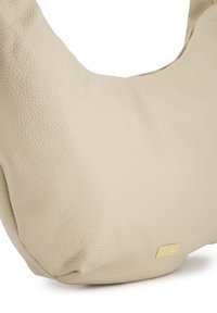 Cremfarbige Lederhandtasche mit strukturiertem Oberflächen, geschwungener Form und kleinem goldfarbenem Logoakzent. Mit Reißverschluss oben.