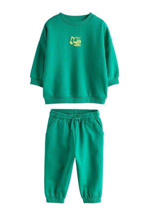 Grüner Kinderpullover und passende Hosen mit elastischem Bund und kleinem gelbem Bagger-Motiv auf der Brust.