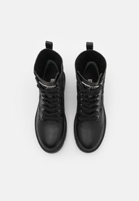 Bottes noires à cheville avec dessus en cuir lisse, col en tissu texturé, bout rond, lacets à l'avant et languette de tirage. Dispose d'œillets métalliques.