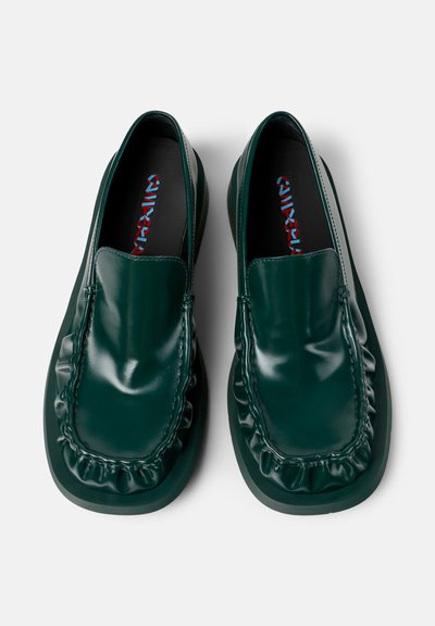 Ein Paar dunkelgrüne, glänzende Leder-Loafers mit quadratischen Zehen und gerafften Details entlang der vorderen Kante auf einem weißen Hintergrund.