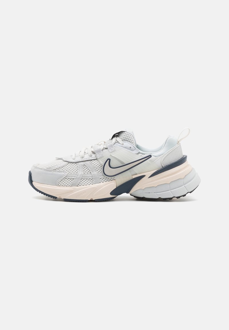 Sportskor med en ljusgrå mesh-övre, marinblå detaljer, en tjock vit mellansula och en strukturerad svart gummiskal.