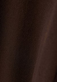 Gros plan d'un tissu tricoté marron foncé montrant un tissage fin et régulier ainsi qu'une texture douce.