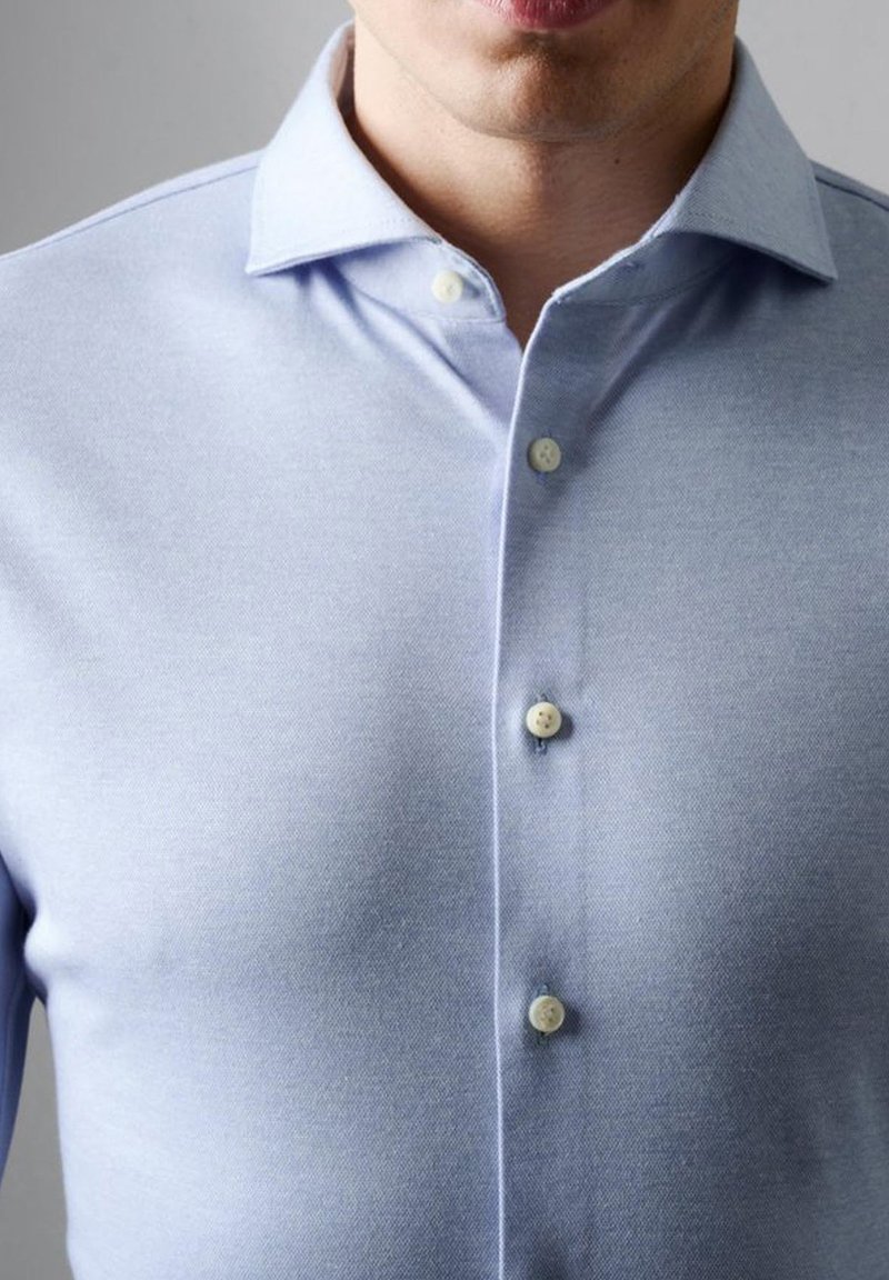 Lichtblauwe button-up shirt van een gestructureerde stof, met een puntige kraag en zes knopen aan de voorkant.