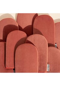 Set von rotbraunen Ofenhandschuhen aus weichem, strukturiertem Stoff. Mit abgerundeter Form und einem sichtbaren Markentag auf einem Handschuh.