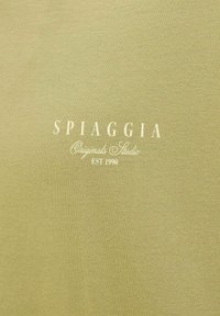 Olivenfarvet stof med en glat tekstur; har hvid tekst "SPIAGGIA Originals Studio EST 1990" trykt tydeligt.