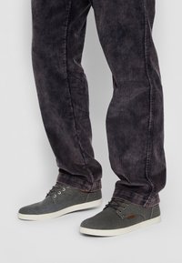 Sneakers di tela grigi con punta rotonda, suola in gomma bianca e lacci grigi. Da abbinare a pantaloni a righe scure con una vestibilità rilassata.