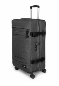 Valigia grigia con ruote, superficie in tessuto strutturato, accessori neri, manico regolabile a scomparsa e scomparti con cerniera sul davanti.