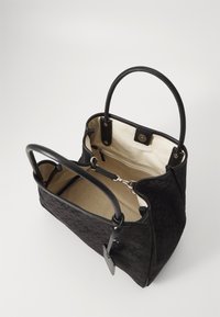Borsa a tracolla nera in tela con motivo floreale, dotata di due manici superiori e un interno beige in contrasto. Include una tasca con zip e dettagli in metallo.
