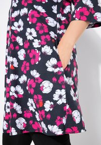 Bloemen tuniek in navy, met roze en witte bloemen. Losse pasvorm, korte mouwen, zijzakken, zachte stof en knielengte ontwerp.
