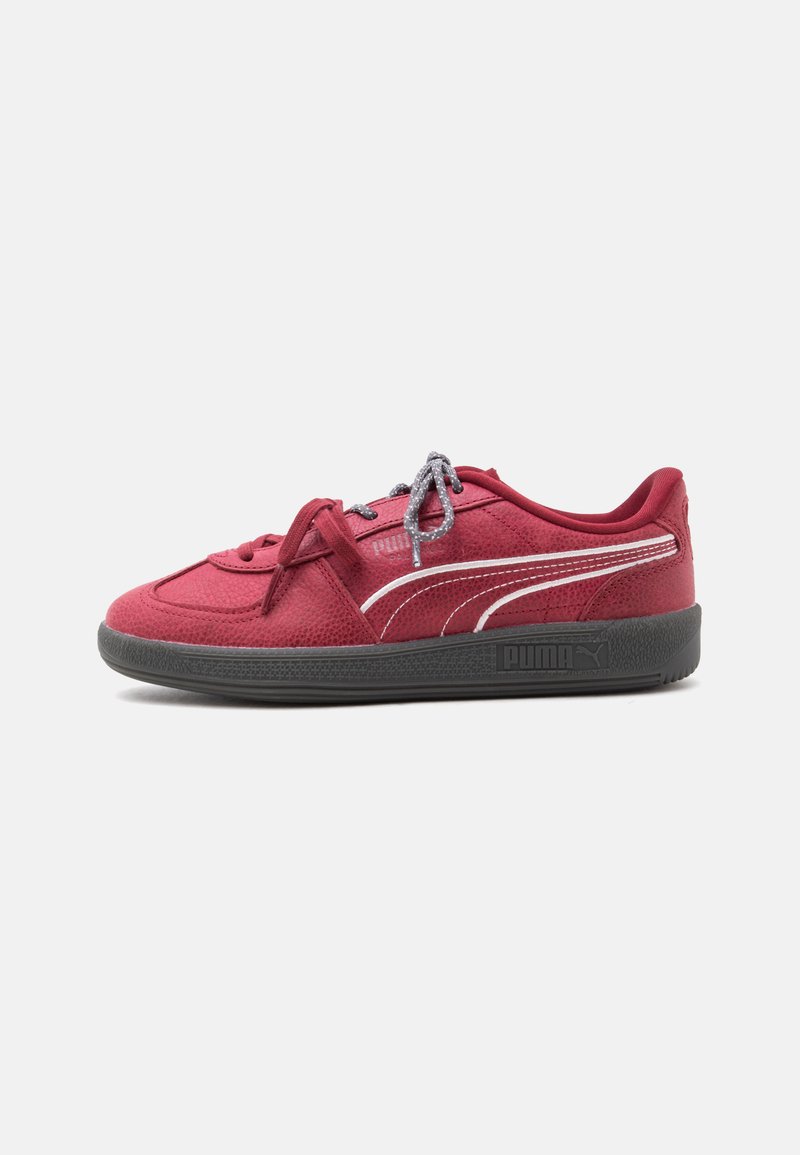 Червена маратонка Puma с черна подметка, бяла странична ивица, текстуриран материал и сиви връзки на бял фон.