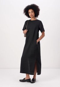 Black, knee-length dress with short sleeves, side pockets, and a slit. Made from a lightweight fabric with a smooth texture.