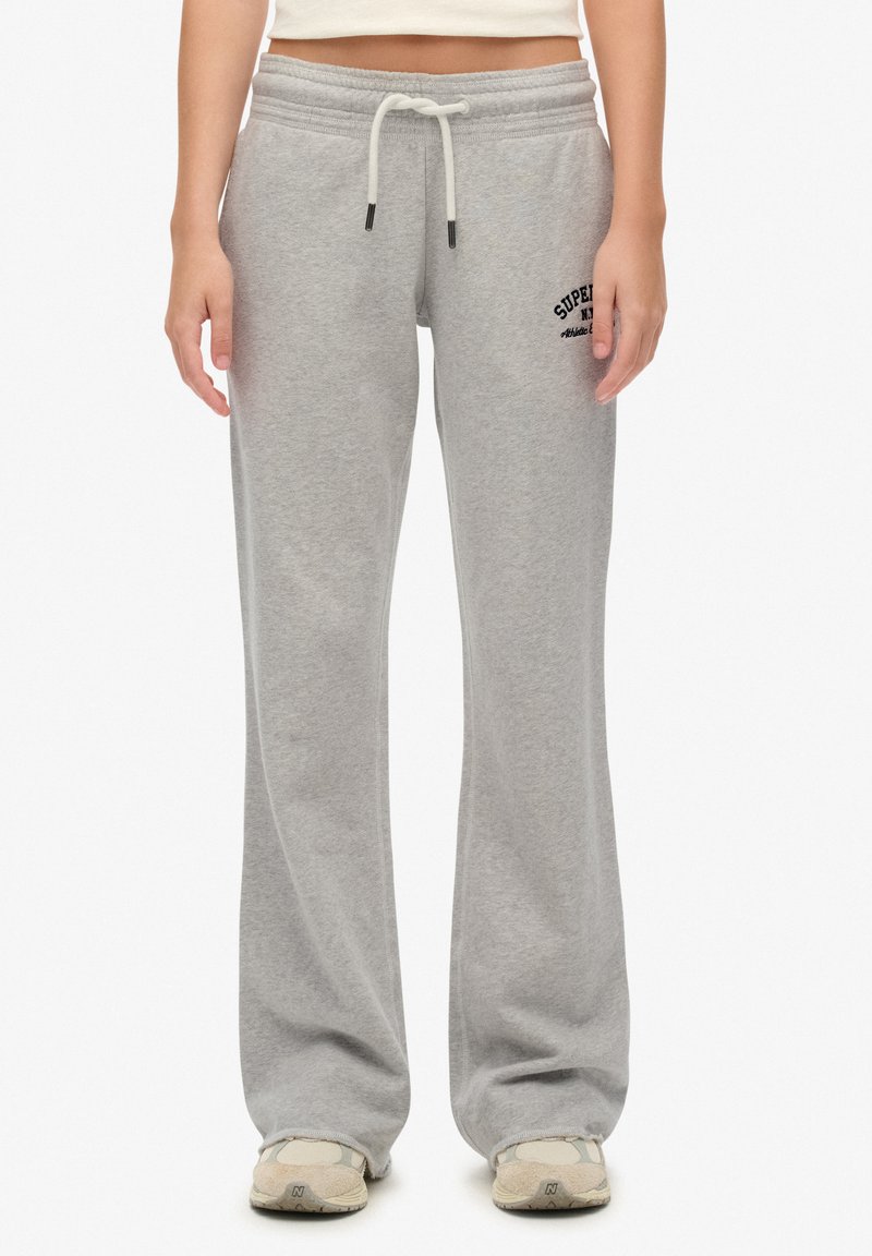 Pantalons de survêtement gris à coupe décontractée, taille élastique, cordon de serrage et petit logo brodé en bas à gauche. Texture douce.