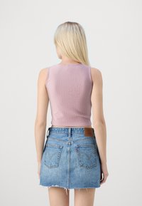 Geribbelde, mouwloze top in zacht lavendel, gecombineerd met een vervaagde denimminirok met een rafelige zoom en twee achterzakken.