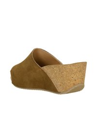 Bruine suede wedge sandal met een lage achterkant en kurken hiel, met een gestructureerde afwerking en gebogen ontwerp. Rubberen zool voor grip.
