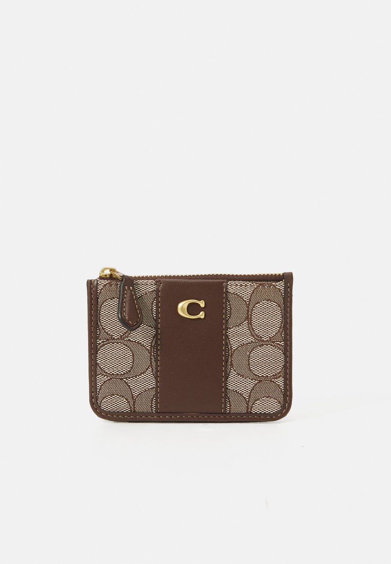 Ce porte-cartes en cuir brun et en mesh présente un motif géométrique, un logo doré et une fermeture à glissière pour un stockage sécurisé. Design compact.