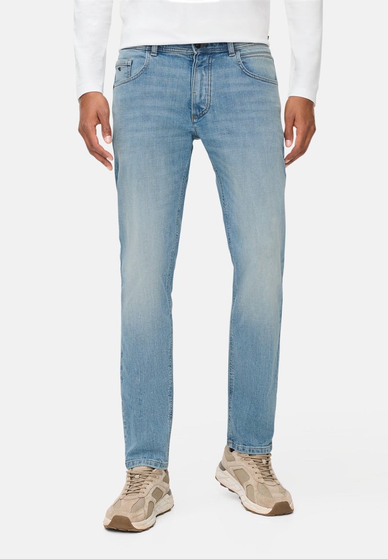 Lichtblauwe denim jeans met een rechte pasvorm, subtiele vervaging, vijf-pocket ontwerp en een knoopsluiting. Gedragen met beige sportschoenen.