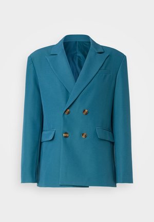 Türkizkék, dupla soros zakó sima anyagból, arany gombokkal, visszavágott hajtókkal és két oldalzsebbel.