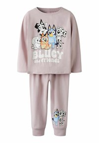 Ljust lila barnpyjamas set med långa ärmar, prydd med tecknade hundkaraktärer och texten "Bluey och vänner" på överdelen samt två karaktärer på byxorna.